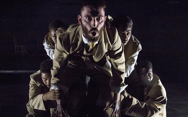 Men in suits kneeling on a stage