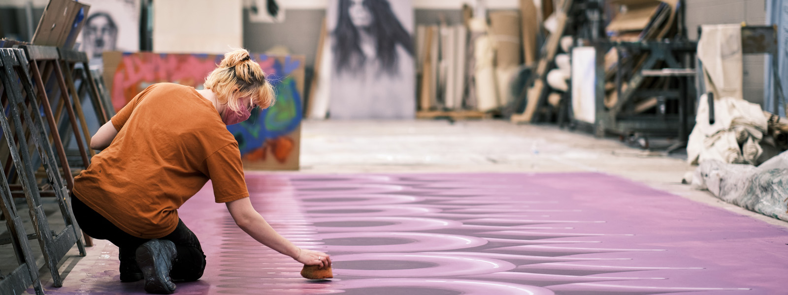 Student sponging paint on to a large scenery canvas