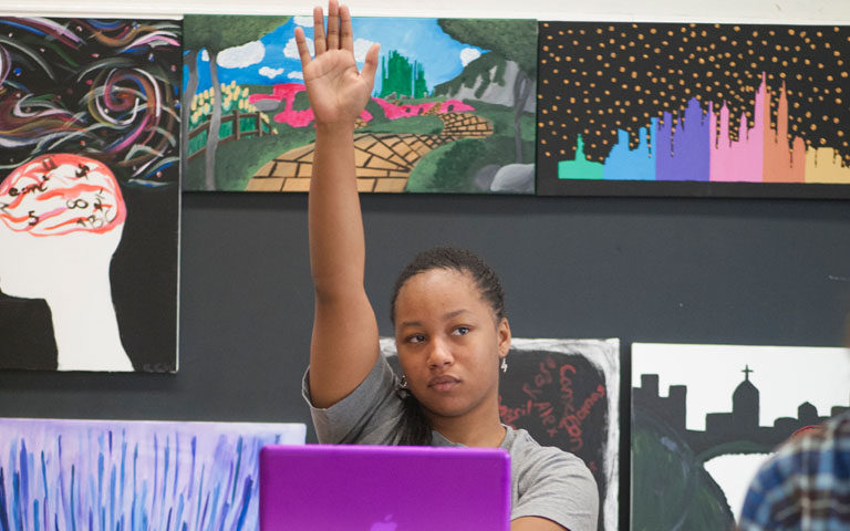 Student raising their hand in a class