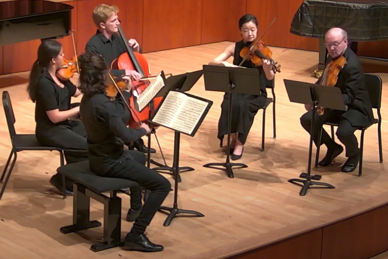 Jake Anderson playing cello in a quintet