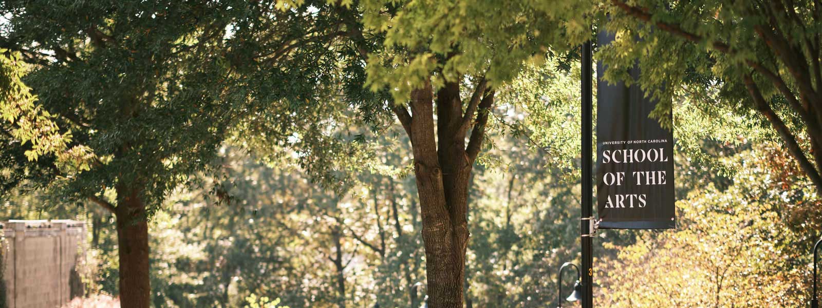  Sign displaying "University of North Carolina School of the Arts" in bold letters against a background of trees.